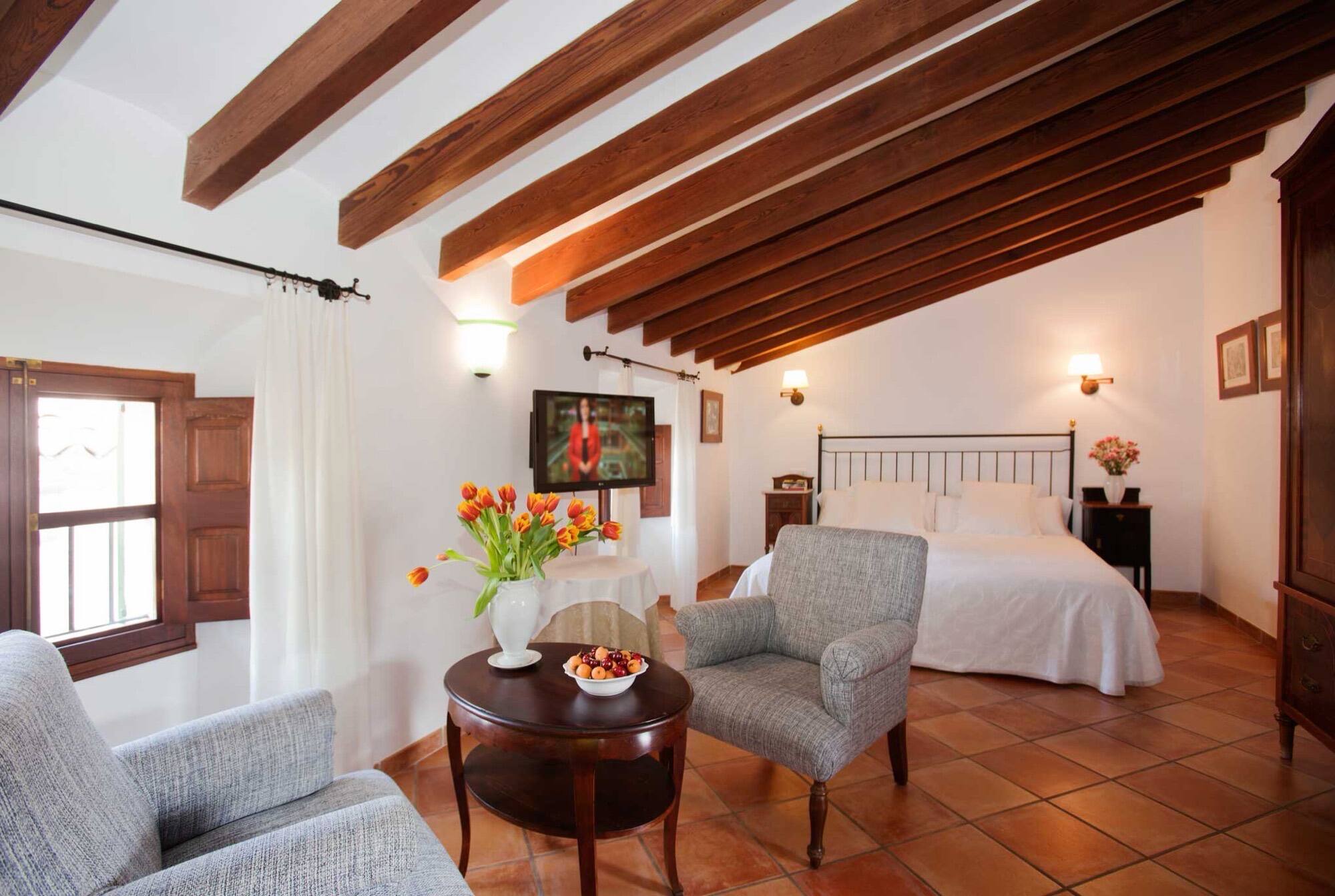 A large suite with armchairs around a round table set with fruit and tulips.